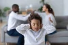 Young child covering his ears, parents arguing